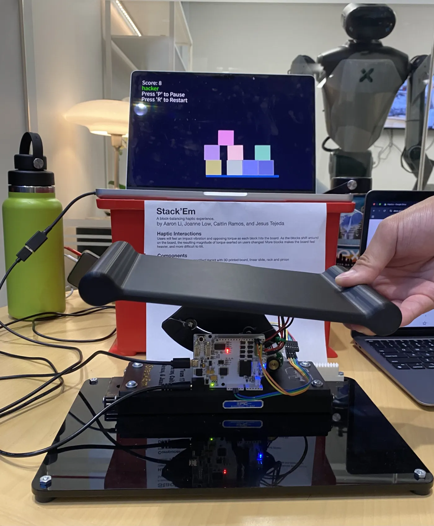 The Stack'em haptic platform controller in front of a screen showing stacked virtual blocks