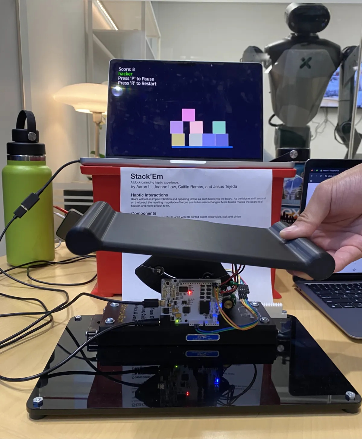 The Stack'em haptic platform controller in front of a screen showing stacked virtual blocks